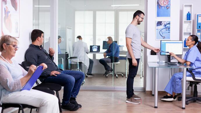 Young Man Talking with Nurse in Hospital Reception